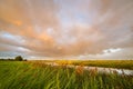 Beautiful rainbow and orange colored sky as a rain shower moves over the dutch countryside Royalty Free Stock Photo