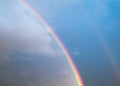 Double rainbow in the sky with clouds and birds