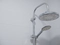 Double shower heads with chrome finish in clean bathroom with pure white ceramic tiles. close-upimage with copy space