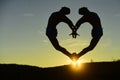 Double silhouette of dancer making heart shape on sunset background