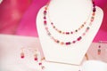 Double-stranded gemstone necklace and matching earrings on a white display stand