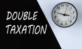 DOUBLE TAXATION - words on black background and alarm clock on white