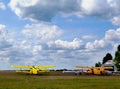 Double winged yellow airplanes in rural air field. blue sky and white clouds. Royalty Free Stock Photo