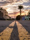 Double yellow lines on the street leading to a power line tower against sunset sky Royalty Free Stock Photo