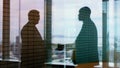 Double your success with collaboration. Silhouette shot of two businesspeople shaking hands inside an office building.