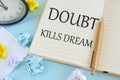 Doubt kills dream, on bright blue background with colored paper lobs. Modern Inspirational message written in Notebook