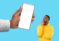 Doubtful Black Guy Looking Aside At Blank Smartphone In Huge Male Hand