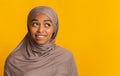 Doubtful black muslim woman in headscarf biting lip and looking aside