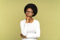 Doubtful black woman touching her chin, frowning, pondering, looking at space doubtfully, studio.