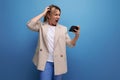 doubtful business woman in a jacket with blond hair holding a credit card on a studio background with copy space