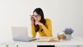 A doubtful and focused Asian female student in eyeglasses is looking at her laptop screen Royalty Free Stock Photo