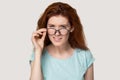 Doubtful red-haired girl take off glasses feeling hesitant