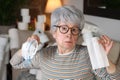 Doubtful senior woman holding two types of masks