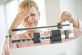 Doubtful Woman Adjusting Weight Scale