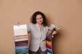 Doubtful woman pointing at fabric samples, having some difficulties on choosing upholstery materials in furniture store