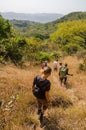 Doucki, Guinea - December 26, 2013: Group of multicultural men and women hiking through dry grass of Doucki highlands Royalty Free Stock Photo