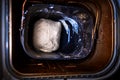 Dough in bread pan of breadmaker at home. Not raised dough preparing for baking in smart bread maker machine loaf-pan