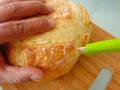 Dough bread slicing close-up view with make hand and green handle ceramic knife