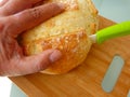 Dough bread slicing close-up view with male hand and green handle ceramic knife