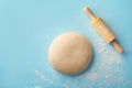 Dough with flour and rolling pin on blue background top view. Bakery concept. Flat lay