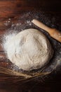 Dough with flour, rolling pin, wheat ears on rustic wooden table top view. Homemade pastry for bread or pizza. Bakery background. Royalty Free Stock Photo