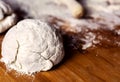 A dough on a flour-soiled wooden board with a blurred rolling pin