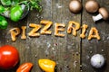 dough letters and vegetables on rustic wooden table, word pizzeria