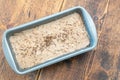 Dough in metal form on wooden table. Dark rye wholemeal bread making process without yest and bakery machine at home Royalty Free Stock Photo