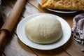 Dough on a plate on a wooden background. The dough is in the shape of a ball on a white plate on a wooden table. Close Royalty Free Stock Photo