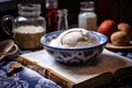 dough rising in a bowl with a recipe book in the background Royalty Free Stock Photo