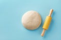 Dough and rolling pin on blue background top view. Bakery concept. Flat lay