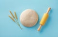 Dough with rolling pin and wheat ears on blue background top view. Bakery concept. Flat lay