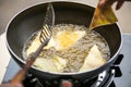 Dough sheet deep frying in very hot oil.