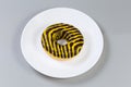 Doughnut with chocolate and yellow glaze on a white dish