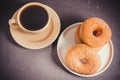 Doughnuts in a plate and a cup of black coffee. Dark table. Top view Royalty Free Stock Photo