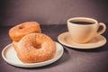 Doughnuts in a plate and a cup of black coffee. Selective focus. Dark background Royalty Free Stock Photo