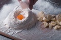 Douth, food, cooking concept - preparing douth - cooking progress and ingridients, Chef pours egg yolk from eggshell into flour Royalty Free Stock Photo