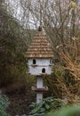 A dovecote shelter for birds and doves pigeons with multiple entrances and a pointed roof on a wooden post Royalty Free Stock Photo