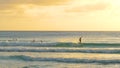 Male surfer catches a wave and rides it to coast on a sunny evening in Barbados