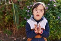 Down syndrome kid sitting on bench with relaxed expression at park Royalty Free Stock Photo