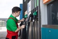 Down syndrome man employee fueling car at gas station.