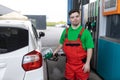 Down syndrome man employee fueling car at gas station.