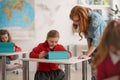 Down syndrome schoolgirl using tablet with help of teacher during class at school, integration concept. Royalty Free Stock Photo