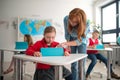 Down syndrome schoolgirl using tablet with help of teacher during class at school, integration concept. Royalty Free Stock Photo