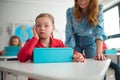 Down syndrome schoolgirl using tablet with help of teacher during class at school, integration concept. Royalty Free Stock Photo