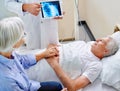 Down to the bare bones of the problem. a sick man in a hospital bed being shown an xray of his shoulder while his wife Royalty Free Stock Photo