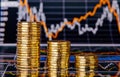 Down trend stacks of golden coins and financial chart Royalty Free Stock Photo