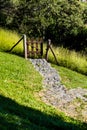 Downhill rocky pathway leading to wooden gate, forest in backgro Royalty Free Stock Photo