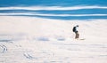 Downhill skier riding down a steep alpine slope on a clear sunny day