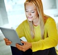 Downloading happiness...an attractive blonde woman relaxing at home with a digital tablet.